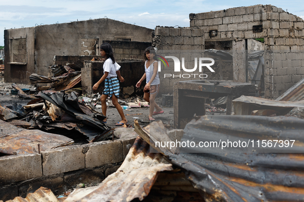 Two children walk near the debris of damaged houses following a huge fire that engulfs at least 800 houses in Bacoor, Cavite, the Philippine...