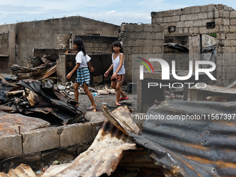 Two children walk near the debris of damaged houses following a huge fire that engulfs at least 800 houses in Bacoor, Cavite, the Philippine...