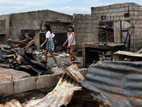 Two children walk near the debris of damaged houses following a huge fire that engulfs at least 800 houses in Bacoor, Cavite, the Philippine...