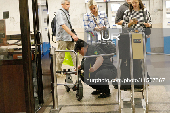 A Kyiv Metro worker measures the length of an electric kick scooter at the Demiivska metro station after the traffic launches following nine...