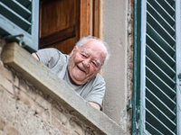 An elderly fan looks out of a window during the 72nd Tour of Tuscany, Coppa Sabatini, in Peccioli, Italy, on September 12, 2024. (