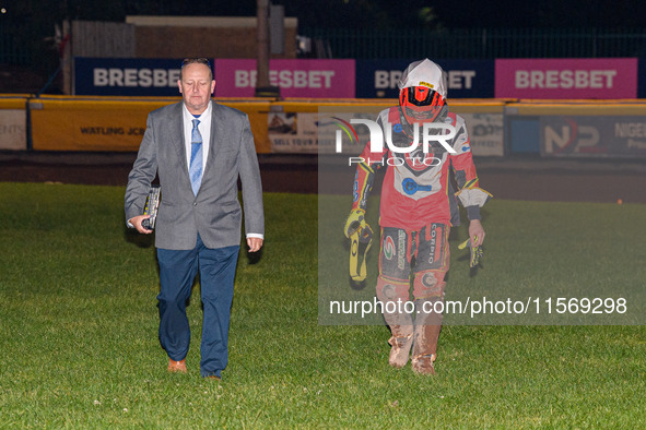 Belle Vue Colts' guest rider Max James (left) walks back to the pits with the Clerk of the Course, Neville Stanley, after his fall during th...