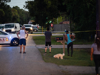 Spectators gather outside the crime scene tape as police investigate a shooting on September 12, 2024. (