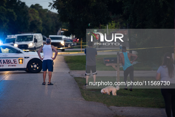 Spectators gather outside the crime scene tape as police investigate a shooting on September 12, 2024. 