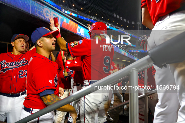 John Giakas #9 of New York's Bravest is congratulated after scoring during the baseball game against the NYPD baseball team in the 'Battle o...