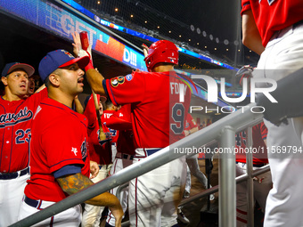 John Giakas #9 of New York's Bravest is congratulated after scoring during the baseball game against the NYPD baseball team in the 'Battle o...