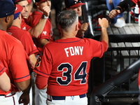 New York's Bravest Dan Quinn #34 is congratulated after scoring during the baseball game against the NYPD baseball team in the 'Battle of Ba...