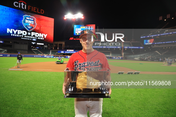 Dan Quinn #34 of New York's Bravest holds up retired golden spikes after playing his final game for FDNY after the 'Battle of Badges' at Cit...