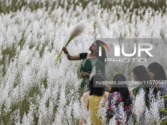 A girl holds a kans grass flower in a kans grass flower field in the afternoon in Dhaka, Bangladesh, on September 13, 2024. (