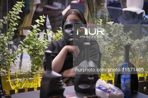 A young Iranian woman holds a mask in front of her face while playing Mafia, a party game, at a cafe at Adrenaline Park in Tehran, Iran, on...