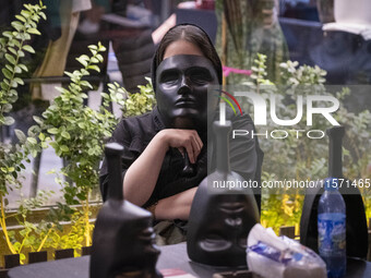 A young Iranian woman holds a mask in front of her face while playing Mafia, a party game, at a cafe at Adrenaline Park in Tehran, Iran, on...