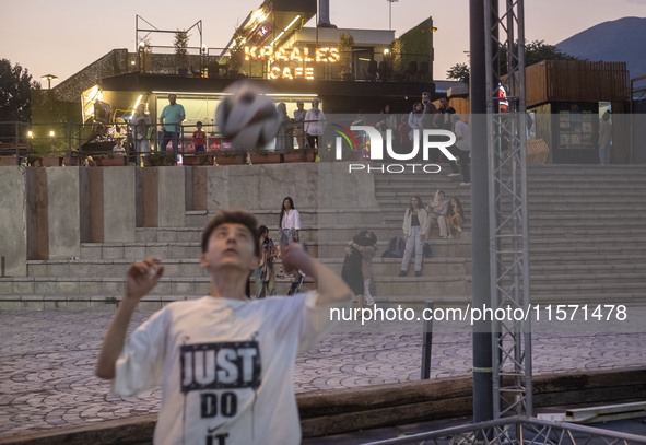 A young Iranian man performs with a ball at Adrenaline Park while youths and families stand together in Tehran, Iran, on September 13, 2024....