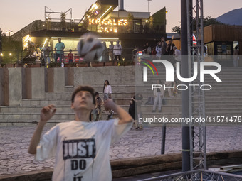 A young Iranian man performs with a ball at Adrenaline Park while youths and families stand together in Tehran, Iran, on September 13, 2024....