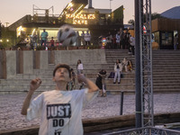 A young Iranian man performs with a ball at Adrenaline Park while youths and families stand together in Tehran, Iran, on September 13, 2024....