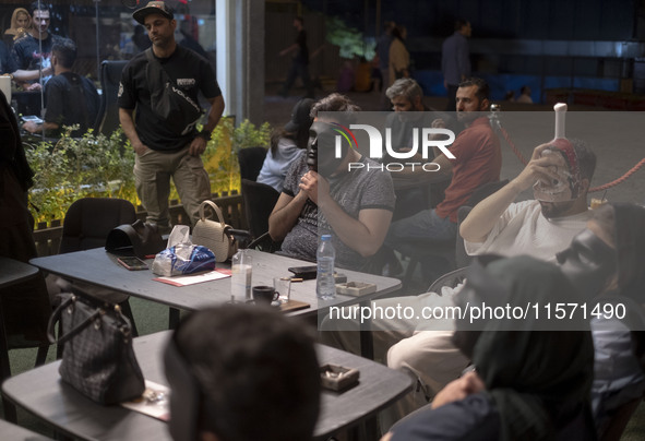 Iranian youths hold masks in front of their faces while playing Mafia, a party game, at a cafe at Adrenaline Park in Tehran, Iran, on Septem...