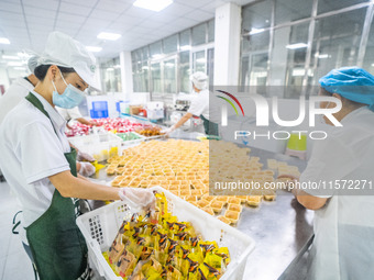 Workers make handmade mooncakes at a food production workshop in Bijie, China, on September 12, 2024. (