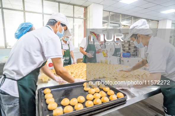 Workers make handmade mooncakes at a food production workshop in Bijie, China, on September 12, 2024. 