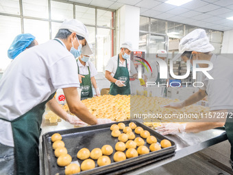 Workers make handmade mooncakes at a food production workshop in Bijie, China, on September 12, 2024. (