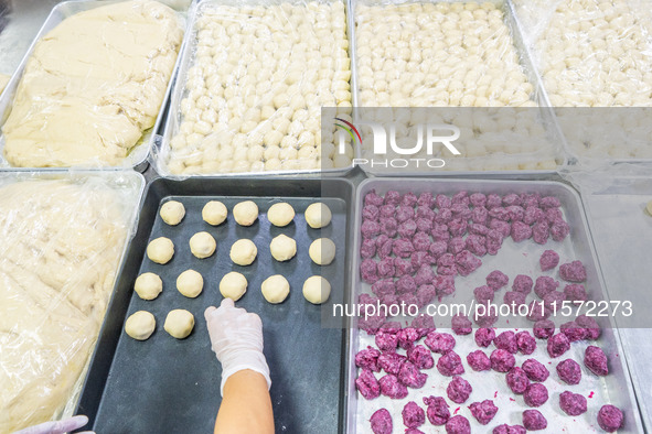 Workers make handmade mooncakes at a food production workshop in Bijie, China, on September 12, 2024. 