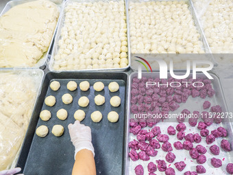 Workers make handmade mooncakes at a food production workshop in Bijie, China, on September 12, 2024. (