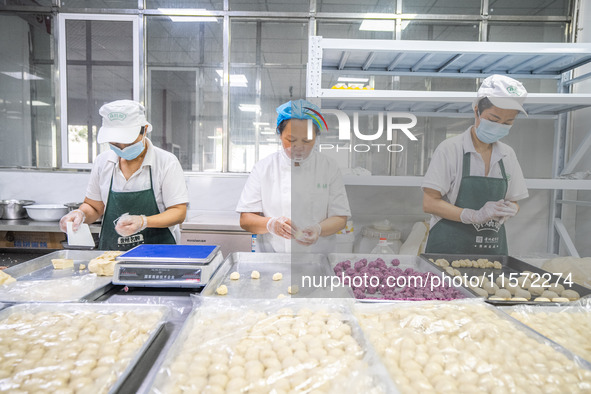 Workers make handmade mooncakes at a food production workshop in Bijie, China, on September 12, 2024. 