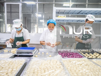 Workers make handmade mooncakes at a food production workshop in Bijie, China, on September 12, 2024. (