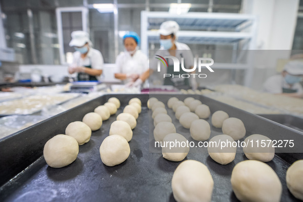 Workers make handmade mooncakes at a food production workshop in Bijie, China, on September 12, 2024. 