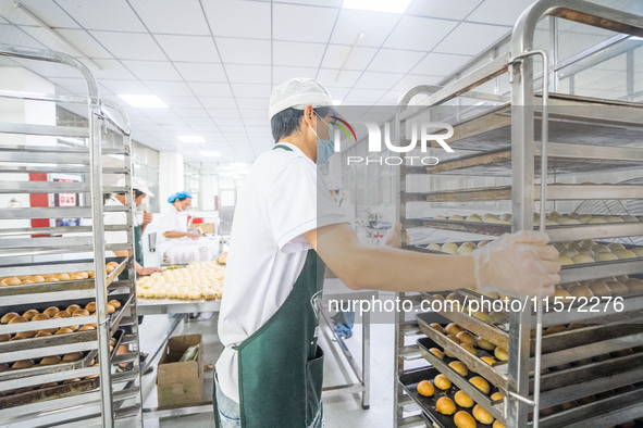 Workers make handmade mooncakes at a food production workshop in Bijie, China, on September 12, 2024. 