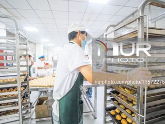 Workers make handmade mooncakes at a food production workshop in Bijie, China, on September 12, 2024. (