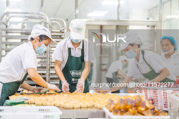 Workers make handmade mooncakes at a food production workshop in Bijie, China, on September 12, 2024. 