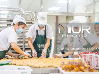 Workers make handmade mooncakes at a food production workshop in Bijie, China, on September 12, 2024. (