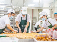 Workers make handmade mooncakes at a food production workshop in Bijie, China, on September 12, 2024. (