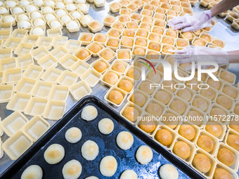 Workers make handmade mooncakes at a food production workshop in Bijie, China, on September 12, 2024. (