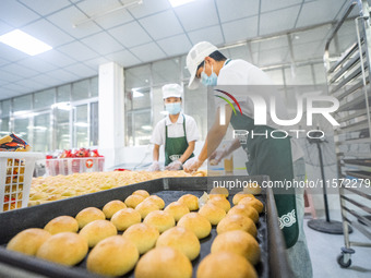 Workers make handmade mooncakes at a food production workshop in Bijie, China, on September 12, 2024. (