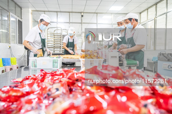 Workers make handmade mooncakes at a food production workshop in Bijie, China, on September 12, 2024. 