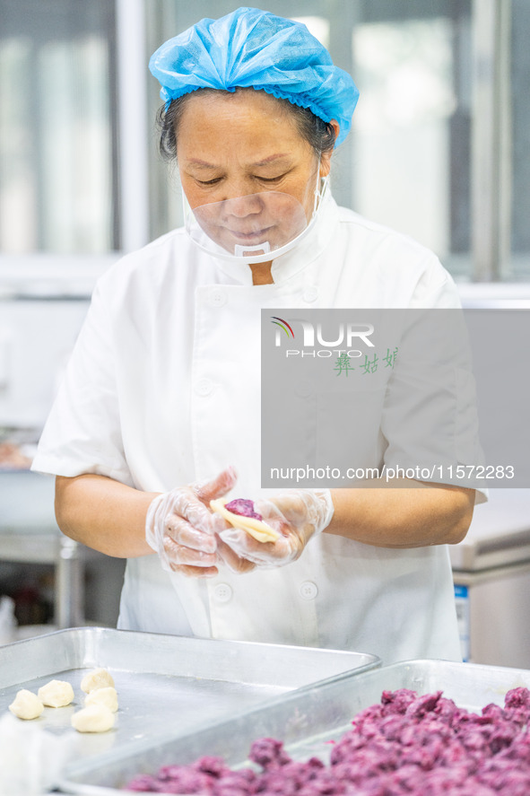 Workers make handmade mooncakes at a food production workshop in Bijie, China, on September 12, 2024. 