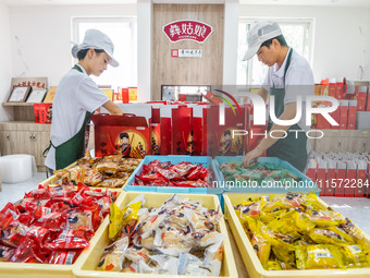 Workers make handmade mooncakes at a food production workshop in Bijie, China, on September 12, 2024. (