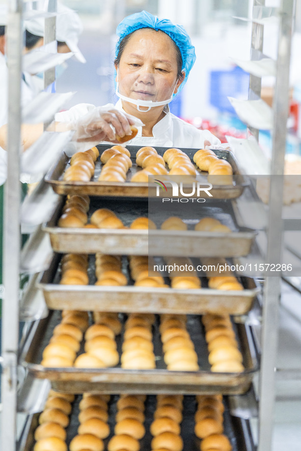 Workers make handmade mooncakes at a food production workshop in Bijie, China, on September 12, 2024. 