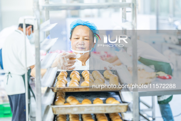 Workers make handmade mooncakes at a food production workshop in Bijie, China, on September 12, 2024. 