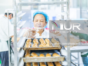 Workers make handmade mooncakes at a food production workshop in Bijie, China, on September 12, 2024. (