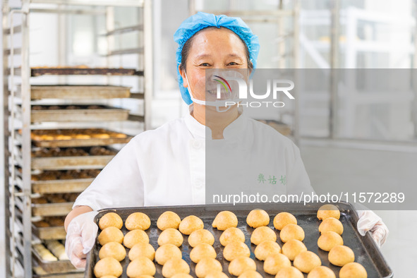 Workers make handmade mooncakes at a food production workshop in Bijie, China, on September 12, 2024. 