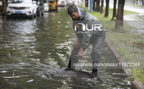 A municipal worker removes flood water after heavy rains in Huai'an, China, on September 14, 2024. 