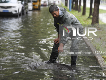 A municipal worker removes flood water after heavy rains in Huai'an, China, on September 14, 2024. (