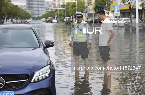 A traffic policeman helps citizens deal with stranded vehicles after a rainstorm in Huai'an, China, on September 14, 2024. 