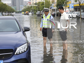 A traffic policeman helps citizens deal with stranded vehicles after a rainstorm in Huai'an, China, on September 14, 2024. (