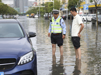 A traffic policeman helps citizens deal with stranded vehicles after a rainstorm in Huai'an, China, on September 14, 2024. (