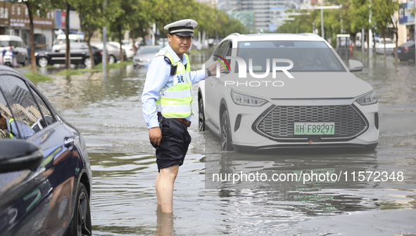 A traffic policeman helps citizens deal with stranded vehicles after a rainstorm in Huai'an, China, on September 14, 2024. 