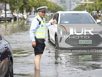 A traffic policeman helps citizens deal with stranded vehicles after a rainstorm in Huai'an, China, on September 14, 2024. (