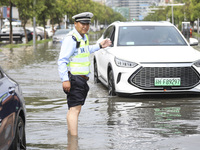 A traffic policeman helps citizens deal with stranded vehicles after a rainstorm in Huai'an, China, on September 14, 2024. (