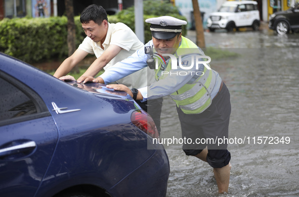 A traffic policeman helps citizens deal with stranded vehicles after a rainstorm in Huai'an, China, on September 14, 2024. 